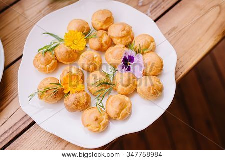 Small Delicious Eclers With Golden Crust. Delicious Sweets On A White Plate.