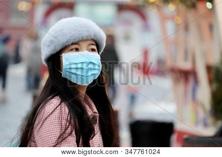 Moscow, Russia - January 2020: Chinese Girl In Protective Medical Mask Standing On A Winter City Str