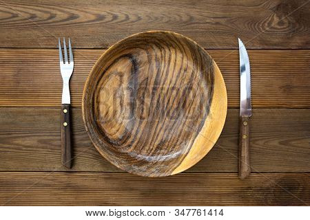 Top View Of Wooden Roud Plate With Fork And Knife, On Wooden Table. Copy Space For Text, Menu, Recip
