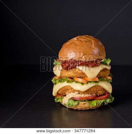 Hamburger With A Double Serving Of Meat, Tomatoes, Salad, Onions On A Wooden Board In A Restaurant.c