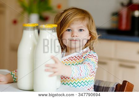Adorable Toddler Girl Drinking Cow Milk For Breakfast. Cute Baby Daughter With Lots Of Bottles. Heal