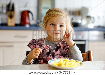 Lovely Toddler Girl Eating Healthy Fried Potatoes For Lunch. Cute Happy Baby Child In Colorful Cloth