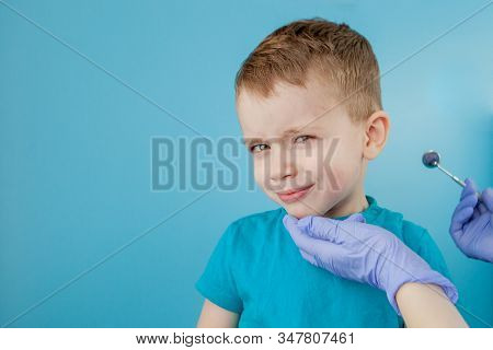 Small Patient Does Not Want To Open The Dentists Mouth On Blue Background. Dantist Treats Teeth. Clo