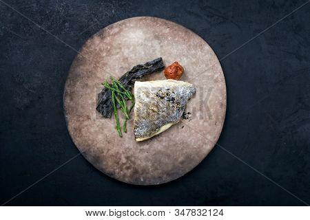 Japanese gourmet fried gilthead fish filet with glasswort, umeboshi and algae as top view on a modern design plate with copy space 