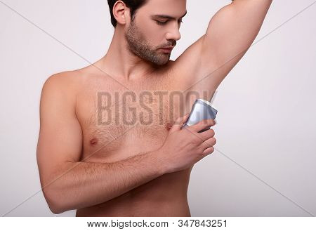 An Athletic Young Sexy Brunette With A Beard Holds A Deodorant In His Hand, Uses Medium Against Swea