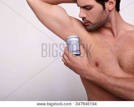 Close-up A Naked Young Man With Topical Hair Puts Dry Deodorant On His Armpit. An Image Of A Pulled-