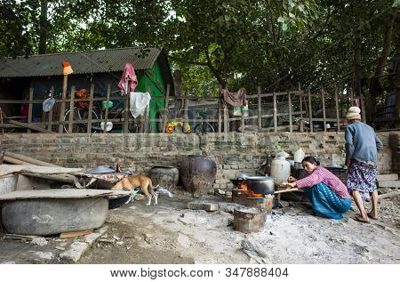Mandalay, Myanmar - January 3, 2019: Woman cooking food in slum area near the Irrawaddy river