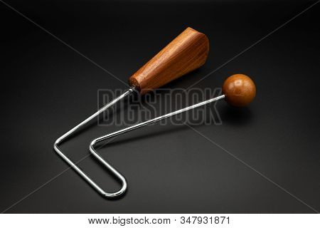Closeup Of A Vibraslap Silver, Brown Wood On Black Underground