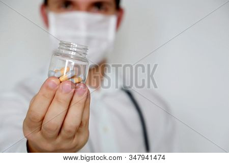 Doctor Giving Pills, Physician In Medical Mask With Bottle Of Capsules. Concept Of Dose Of Drugs, Vi