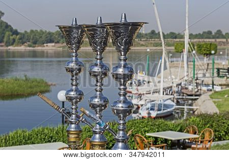 Traditional Egyptian Shisha Water Pipe With Felluca Sailing Boats In Rural Countryside Setting Along