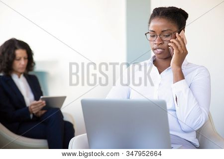 Businesswoman Using Laptop And Talking By Smartphone. Serious Business Woman Working With Lapop Comp