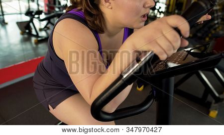 Exhausted Corpulent Female Sitting On Stationary Bike And Suffering From Dyspnea