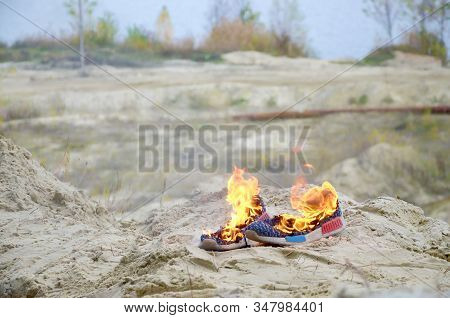 Burning Sports Sneakers Or Gym Shoes On Fire Stand On Sandy Beach Coast. Athlete Burned Out. Physica