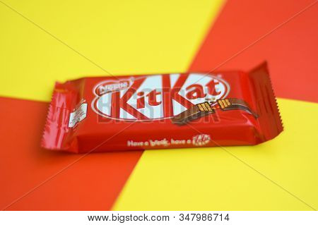 Kit Kat Chocolate Bars In Red Wrapping Lies On Yellow And Red Background. Kit Kat Created By Rowntre