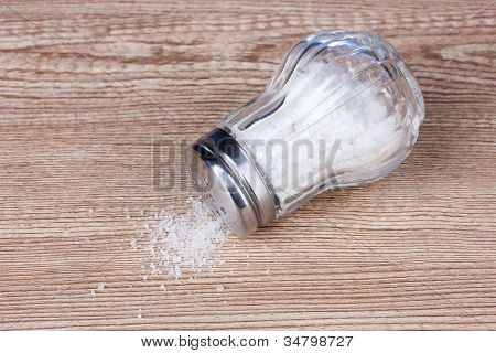 Glas saltcellar med salt på træ baggrund