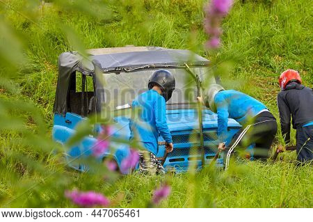 4x4 Off-road Car Competitions. A Team In Helmet On A Blue Car Gets Out Of An Extreme Trap. Getting S