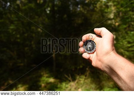 Compass In Hand At Forest. Tourist Compass For Orientation On The Terrain. Magnetic Declination Alcu