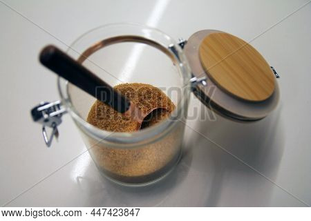 Close Up Of A Isolated Glass And Wood Cane Sugar Jar With A Copper And Wood Spoon With Its Lock