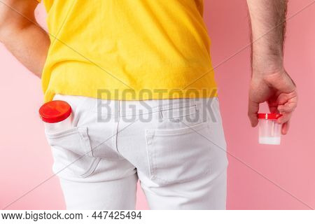 A Man With His Back Turned Shows The Back Pocket Of White Jeans With A Plastic Jar For Analysis, And