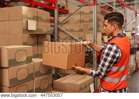 Worker Stacking Cardboard Boxes In Warehouse. Wholesaling