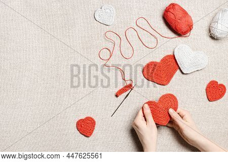 Red Knit Hearts For Valentines Day, Woman Hands Knit Work Crochet Heart, Hook, Yarn On Cloth Backgro