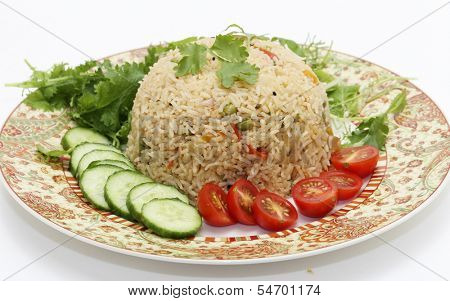A healthy tomato (thakkali) biriyani with a salad of cucumber, cherry tomatoes and some fresh leaves. This biryani, which incorporates onion, peas and a capsicum  ball pepper, is a South Indian dish.