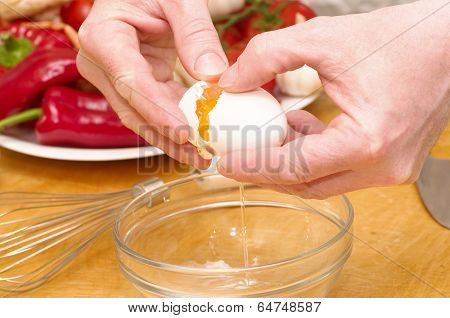 The chef, Baker cracking an egg in a transparent mixing bowl
