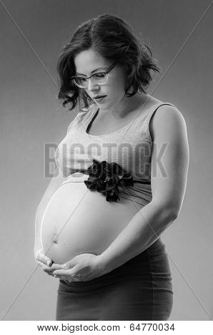 pregnant woman in black and white background with hands on her belly
