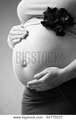 pregnant woman on background with hands on her belly in monochrome