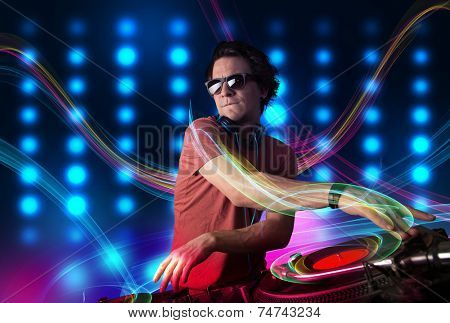 Attractive young Dj mixing records with colorful lights