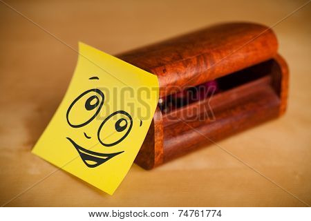 Drawn smiley face on a post-it note sticked on a jewelry box