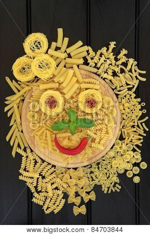 Pasta selection with abstract smiley face on a wooden board over dark wood background..