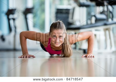 Gorgeous blonde woman warming up and doing some push ups a the gym