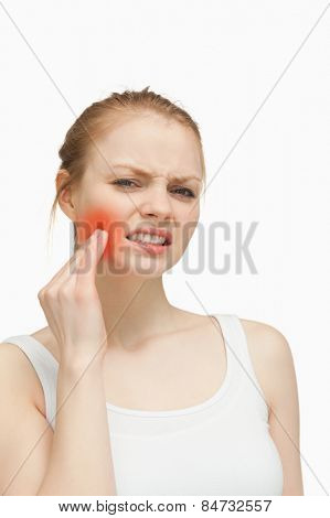 Young woman massaging her jaw against white background