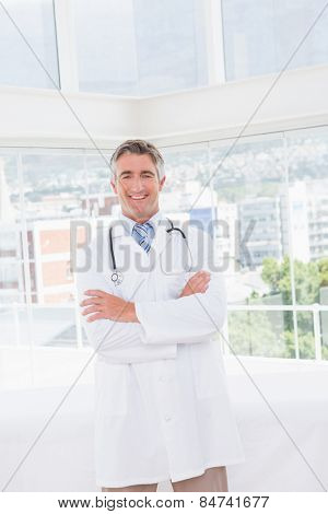 Doctor smiling at camera with arms crossed in medical offie