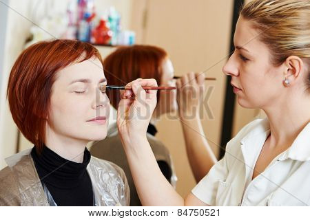 Makeup technique. specialist works with mascara eyelashes of redheaded woman in beauty salon