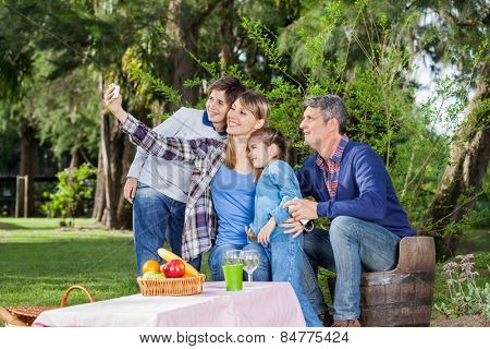 Happy family taking selfportrait through smartphone at campsite