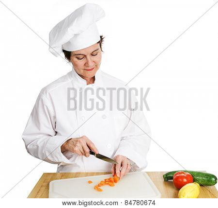 Pretty female chef chopping vegetables on a cutting board.  Isolated on white.  