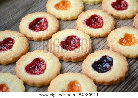 Homemade cookies with heart shaped jam on wooden table