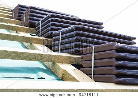 A roof under construction. Stacks of tiles ready to be fasten on the wooden construction. Waterproof and solid rooftop.