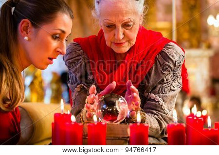 Female Fortuneteller or esoteric Oracle, sees in the future by looking into their crystal ball answering questions from client