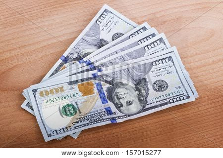 several hundred dollar bills on a wooden table