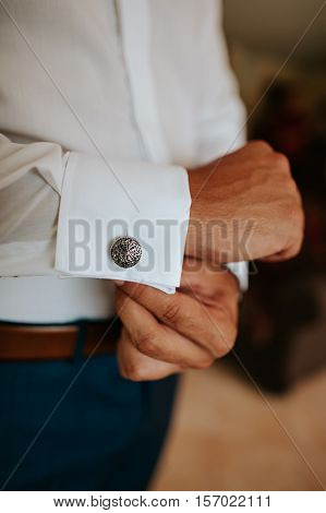 Man putting on cuff-links as he gets dressed in formal wear