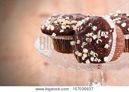 Muffins with chocolate glaze on glass tray.