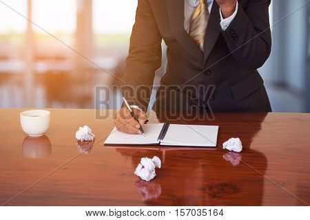 Business man talking about working on smart phone in office. Young business man make plans to work. Coffee cup on wood table in office.