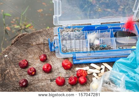 Fishing tackle next to some acerolas fruit cigarette butts and some plastic bags.