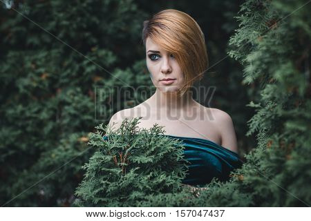 Girl standing among the trees in the forest. She looks away