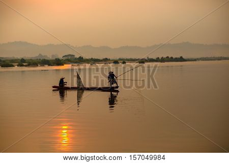 Silhouette Two fishermen people on aboard were catch fish in the Mekong River morning time