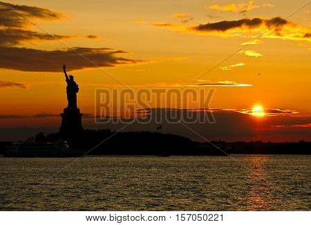 The Statue of Liberty silhouette against crimson sunset