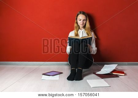 Young student girl studying sitting on the bag-chair near books and tablet pc